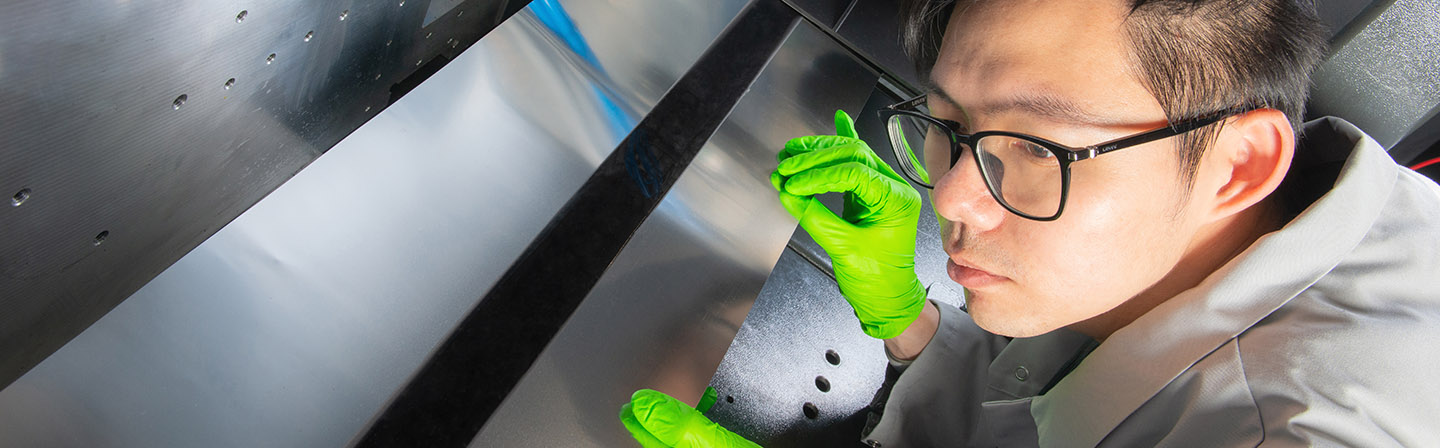 Wissenschaftler prüft die Qualität der Elektrodenbeschichtung an einer Rolle-zu-Rolle-Anlage