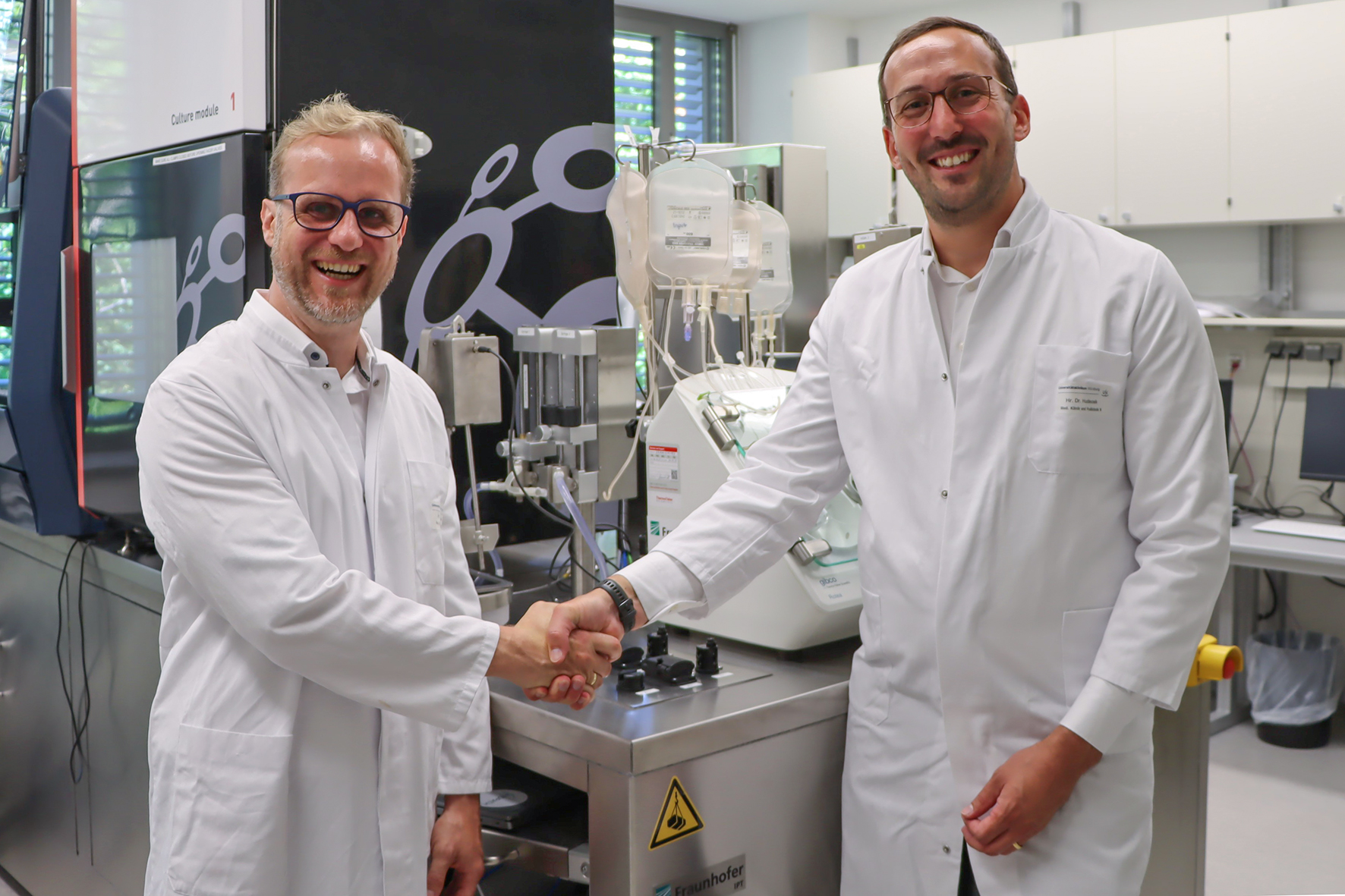 Ready for the start of ATMP production at the point of care: Prof. Dr. Michael Hudecek, Chair of Cellular Immunotherapy at University Hospital Würzburg and Head of the Department of Cellular Immunotherapy at Fraunhofer IZI, welcomes Dr. Bastian Nießing, Head of department Bio-adaptive Production at Fraunhofer IPT, who delivered the AIDPATH platform to its final location.